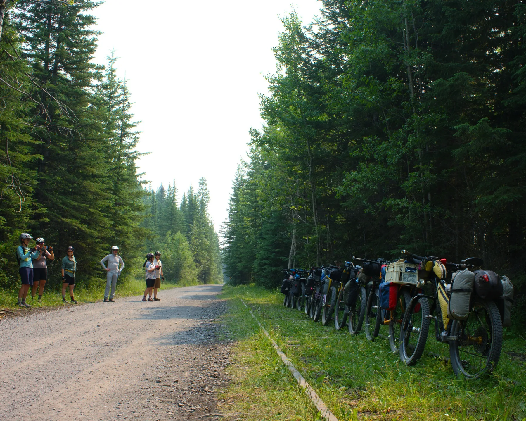 Bikepackers and loaded bikes gathered beside an Alberta rail corridor