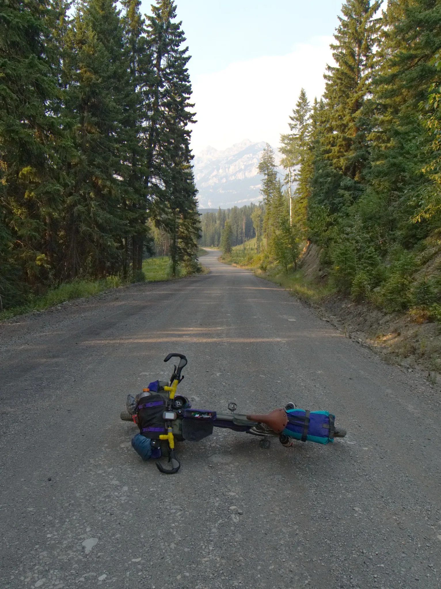 Loaded bike lying on a gravel road with mountains ahead